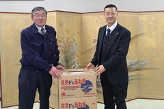特定非営利活動法人くろいし（右）へ食材提供する吹田常務（左）